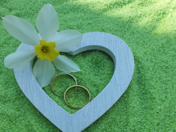 Weißes Herz und Trauringe aus Holz mit zarten Blüten in kleinen Steinen — Stockfoto