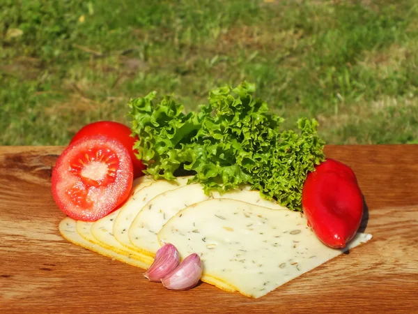 Свежевырезанные кусочки сыра на дубовой доске — стоковое фото