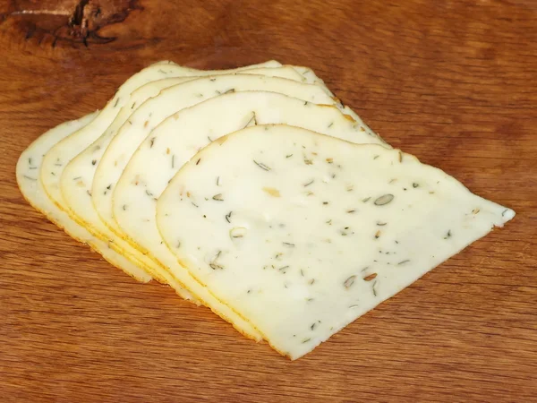 Tranches de fromage fraîchement coupées sur une planche de chêne — Photo