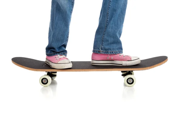 Holky nohy v jean a růžové tenisky na koni skateboard na bílém pozadí — Stock fotografie