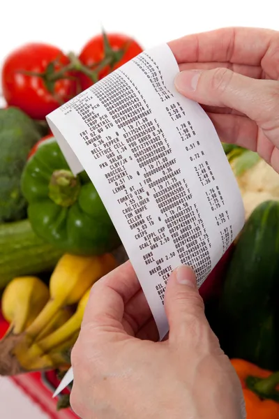 Grocery receipt over a bag of vegetables — Stock Photo, Image