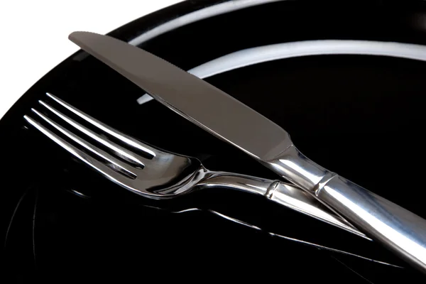 A fork and a knife on a black plate — Stock Photo, Image