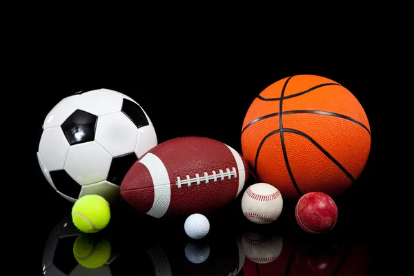 Bolas esportivas sortidas em um fundo preto — Fotografia de Stock