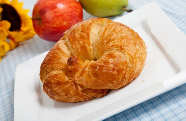Ein Croissant auf einem weißen Teller mit Äpfeln und Sonnenblumen — Stockfoto