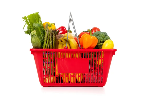 Červený nákupní košík se zeleninou na bílém pozadí — Stock fotografie