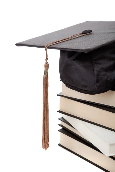 Berretto di laurea in cima a una pila di libri su bianco — Foto Stock