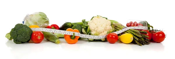 Ряд овощей и лента мера на белом — стоковое фото