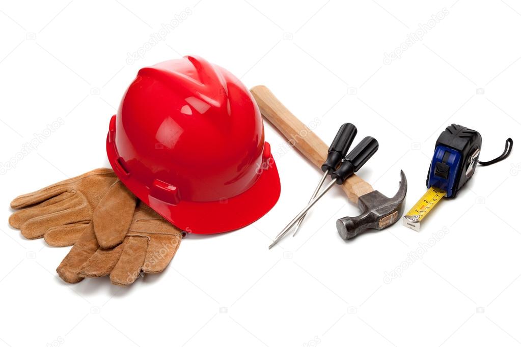 A red hard hat and leather work gloves with tools on white