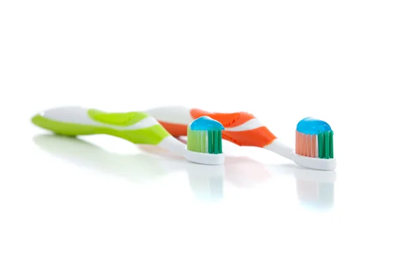 Green and orange toothbrushes on a white background — Stock Photo, Image