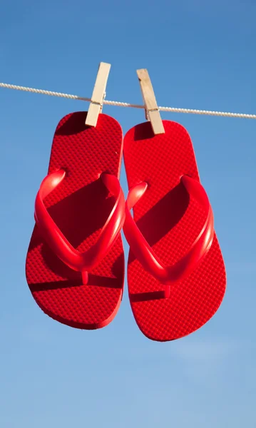 Um par de chinelos vermelhos contra um céu azul — Fotografia de Stock