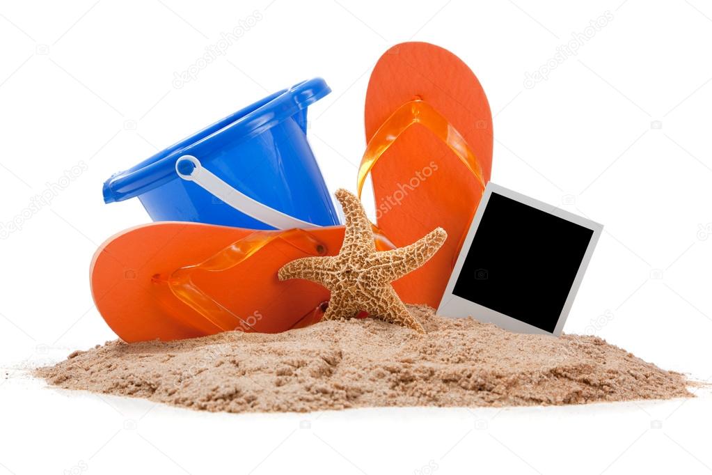 Beach scene with flipflops, sand, bucket and starfish