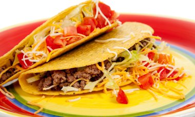 beyaz zemin üzerinde bir tabakta iki tacos