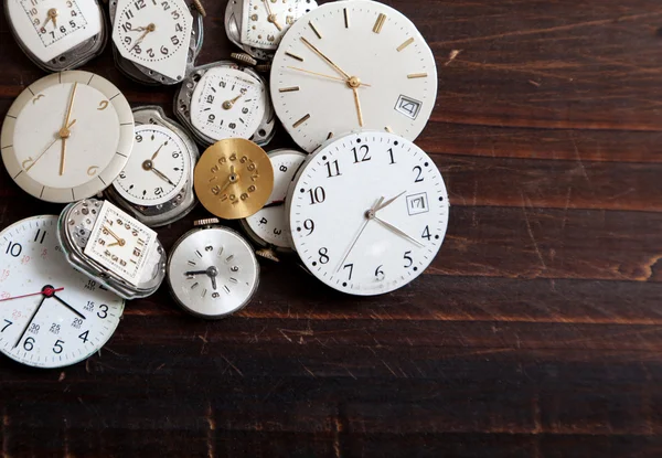 Un assortimento di volti orologio da polso su uno sfondo di legno — Foto Stock