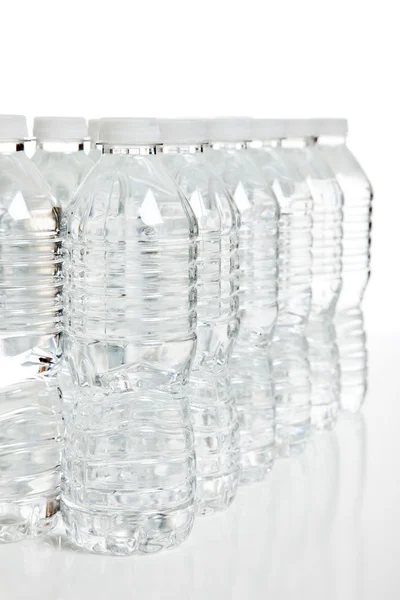 Row of plastic water bottles on white — Stock Photo, Image