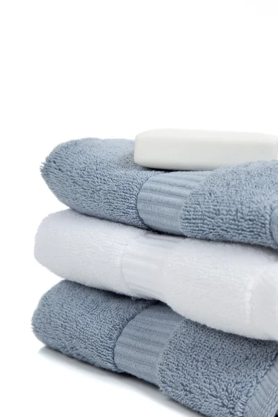 Grijze blauwe en witte handdoeken met een stuk zeep op wit met kopie ruimte — Stockfoto