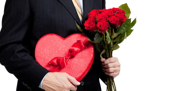 Homem segurando rosas e coração vermelho com chocolates em branco — Fotografia de Stock