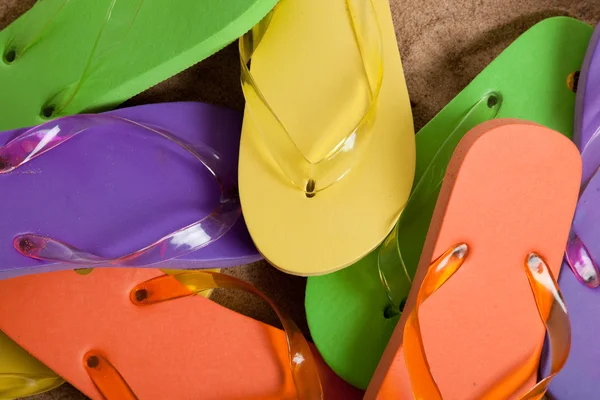 Verschiedene farbige Flipflops auf Sand — Stockfoto