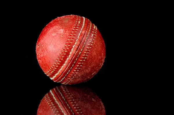 Siyah zemin üzerine kırmızı kriket topu — Stok fotoğraf