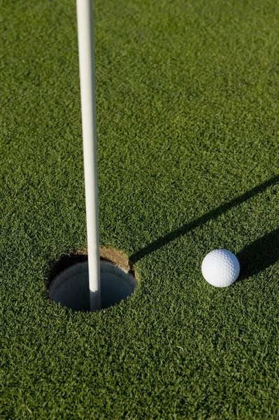 Bola de golfe perto de buraco — Fotografia de Stock