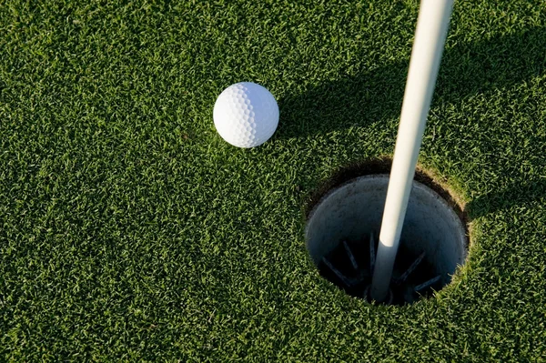 Bola de golfe perto de buraco — Fotografia de Stock