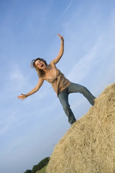 Mooi meisje permanent op baal hooi benadrukkend uit — Stockfoto