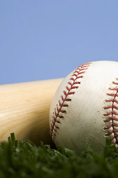 Baseball auf Gras mit Schläger gegen blauen Himmel — Stockfoto