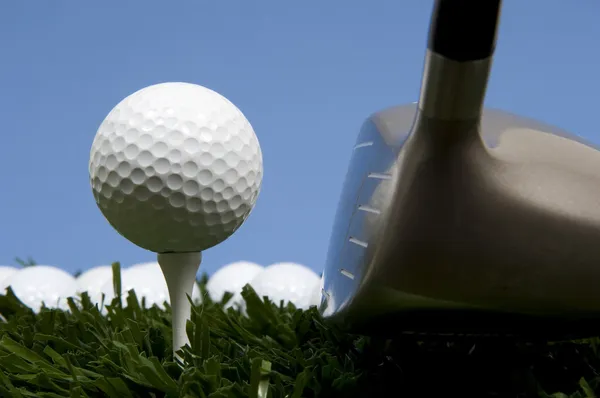 Golf ball on tee on grass with driver — Stock Photo, Image