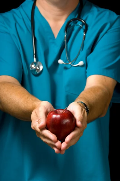 Médico oferecendo maçã — Fotografia de Stock