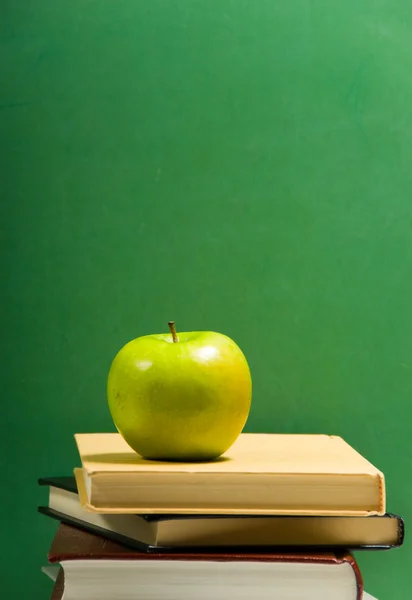 School books on green with apple — Stock Photo, Image