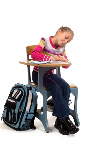 Mladá dívka u stolu ve škole na bílém pozadí — Stock fotografie