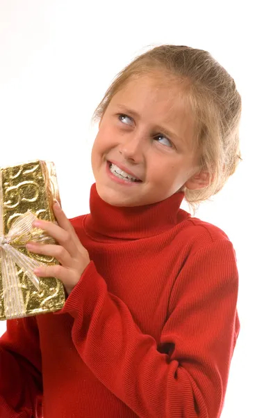 Young girl in red shaking gold Christmas present — Stock Photo, Image