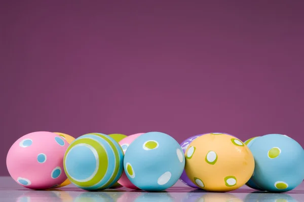 Huevos de Pascua de colores brillantes sobre fondo rosa — Foto de Stock
