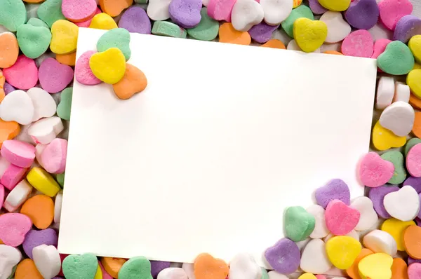 Tarjeta de nota en blanco rodeada, enmarcada por corazones de caramelo Imagen de stock