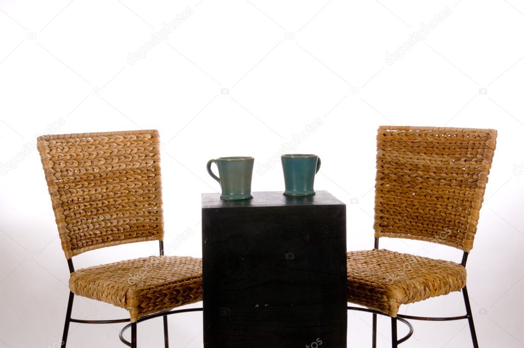 Two empty chairs with two cups of coffee upon the table