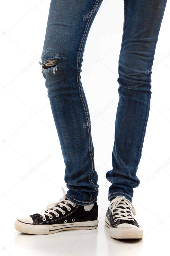 Legs with jeans and retro black sneakers on a white background