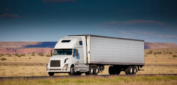 Semi-vrachtwagen op de weg in de woestijn — Stockfoto