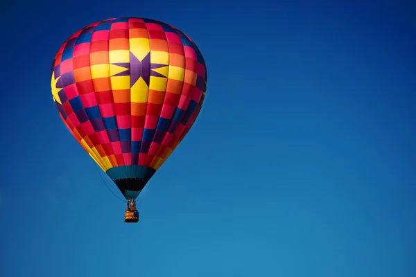 Gökyüzü mavi bir arka plan ile parlak renkli sıcak hava balonu — Stok fotoğraf