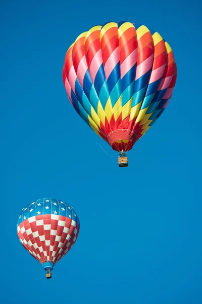 Gökyüzü mavi arka plana sahip iki parlak renkli sıcak hava balonları — Stok fotoğraf