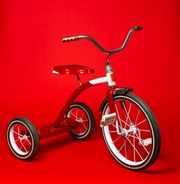 Vintage red tricycle on a bright red background clipart