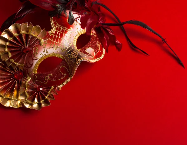 Una maschera veneziana piumata rossa e oro su sfondo rosso — Foto Stock