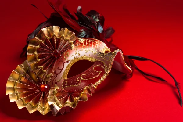 A red and gold feathered Venetian mask on red background — Stock Photo, Image