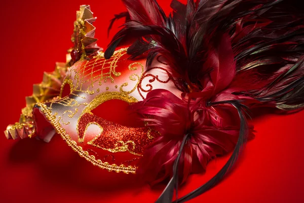 Eine Maske aus rotem, goldenem und schwarzem Mardi Gras auf rotem Hintergrund — Stockfoto
