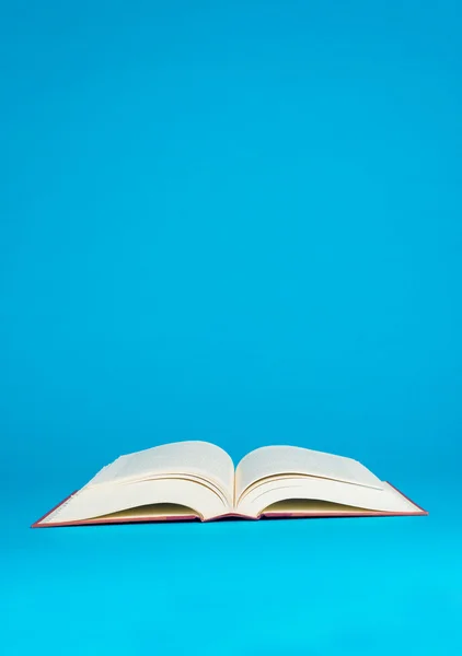 Mavi bir arka plan üzerine açık bir kitap — Stok fotoğraf