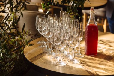 Şampanya ya da uzun saplı şarap için şeffaf cam bardaklar masanın üzerinde güneşle aydınlanan şişenin yanında.