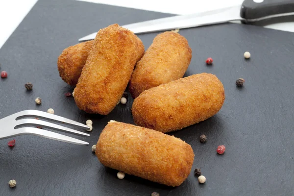 Croquete caseiro tradicional espanhol no garfo com fundo escuro