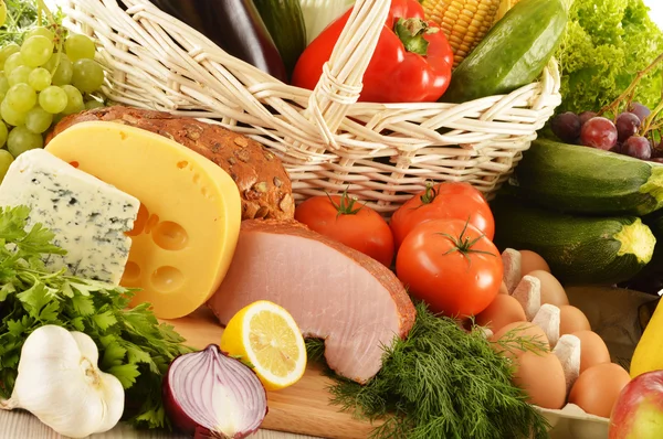 Zusammensetzung mit Lebensmitteln in Weidenkorb auf Küchentisch — Stockfoto