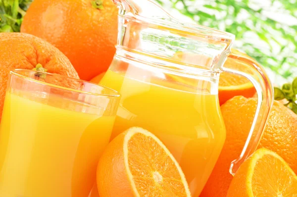 Glass and jug of orange juice and fruits — Stock Photo, Image