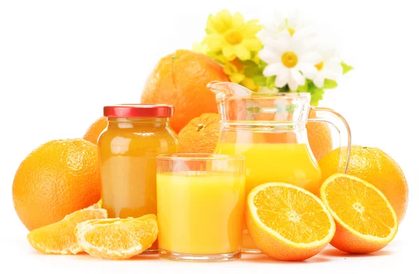 Glass and jug of orange juice, jar of jam and fruits — Stock Photo, Image