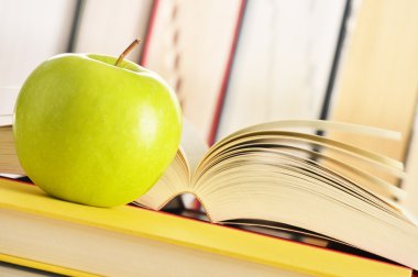 Composition with green apple and books on the table