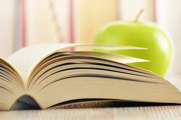 Состав с зеленым яблоком и книгами на столе — стоковое фото